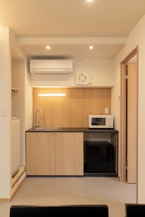 A compact kitchen with a sink, microwave, and built-in oven. - Tora Hotel Nagameguro (Meguro City)