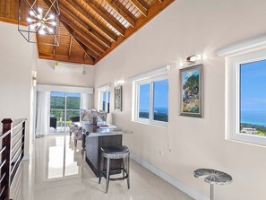 A spacious kitchen with a central island, large windows offering ocean views, and a high ceiling with wooden beams. - BTS1 (Montego Bay)