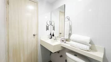 Un baño con inodoro, lavamanos, espejo y toallero.