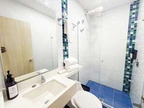 Casa de banho com lavatório, espelho, porta-toalhas e chuveiro.