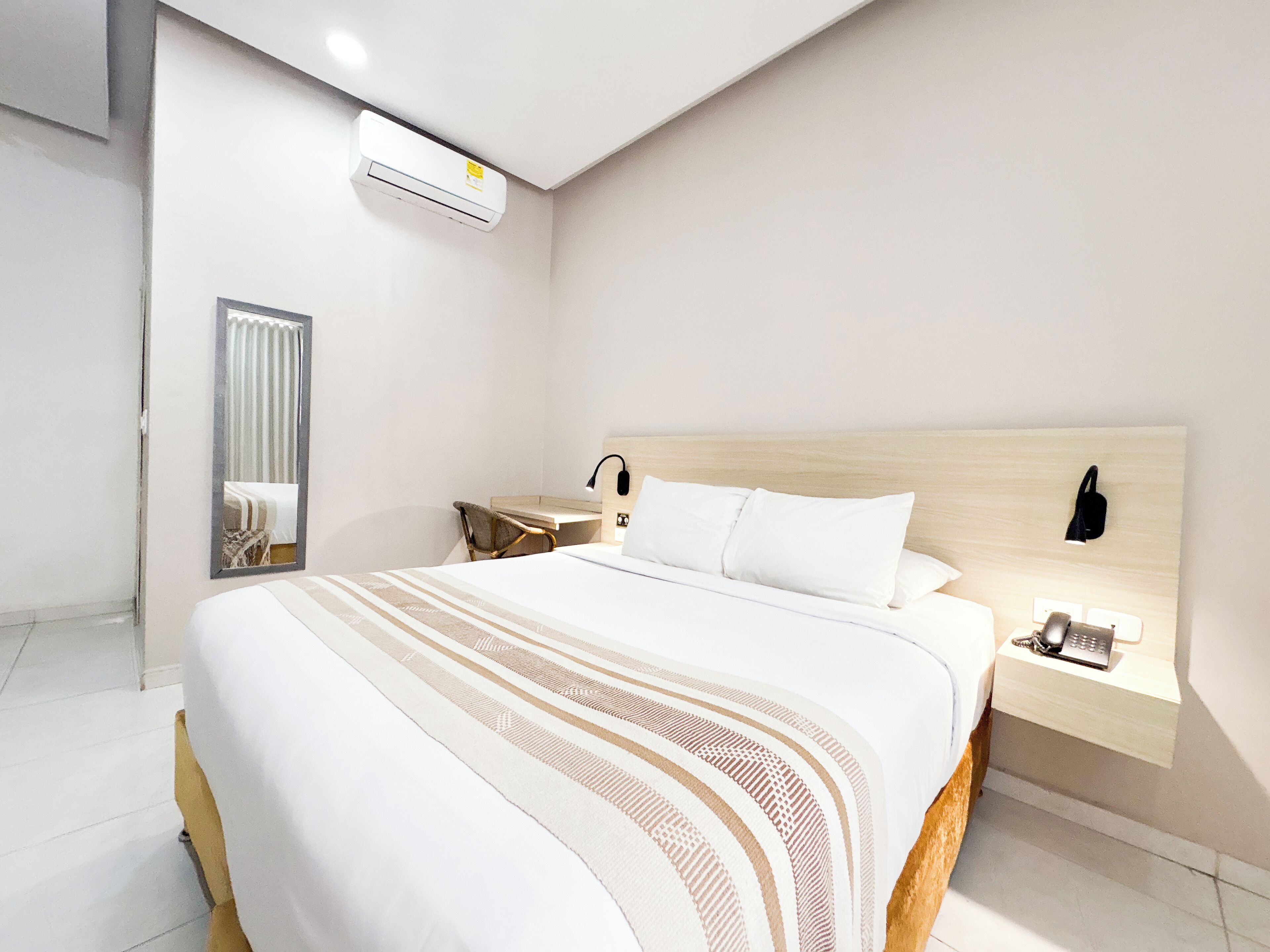 Una camera d'albergo moderna con un letto grande, un comodino, una lampada e un telefono.