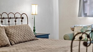 A bed with a quilted cover, a bedside table with a lamp, and a chair with a floral cushion. - Peaceful 3 bedroom home in Tyler (Tyler)