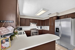 A modern kitchen with stainless steel appliances, wooden cabinets, and a white countertop. - Peaceful 3 bedroom home in Tyler (Tyler)