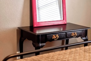 A bedside table with a mirror and two drawers, a bed with a quilted cover, and a wall with a textured finish. - Peaceful 3 bedroom home in Tyler (Tyler)