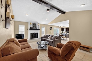 A spacious living room with a fireplace, a dining area, and a kitchen in the background. - Peaceful 3 bedroom home in Tyler (Tyler)