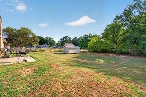 A backyard with a barbecue area, a shed, and a house in the background. - Peaceful 3 bedroom home in Tyler (Tyler)