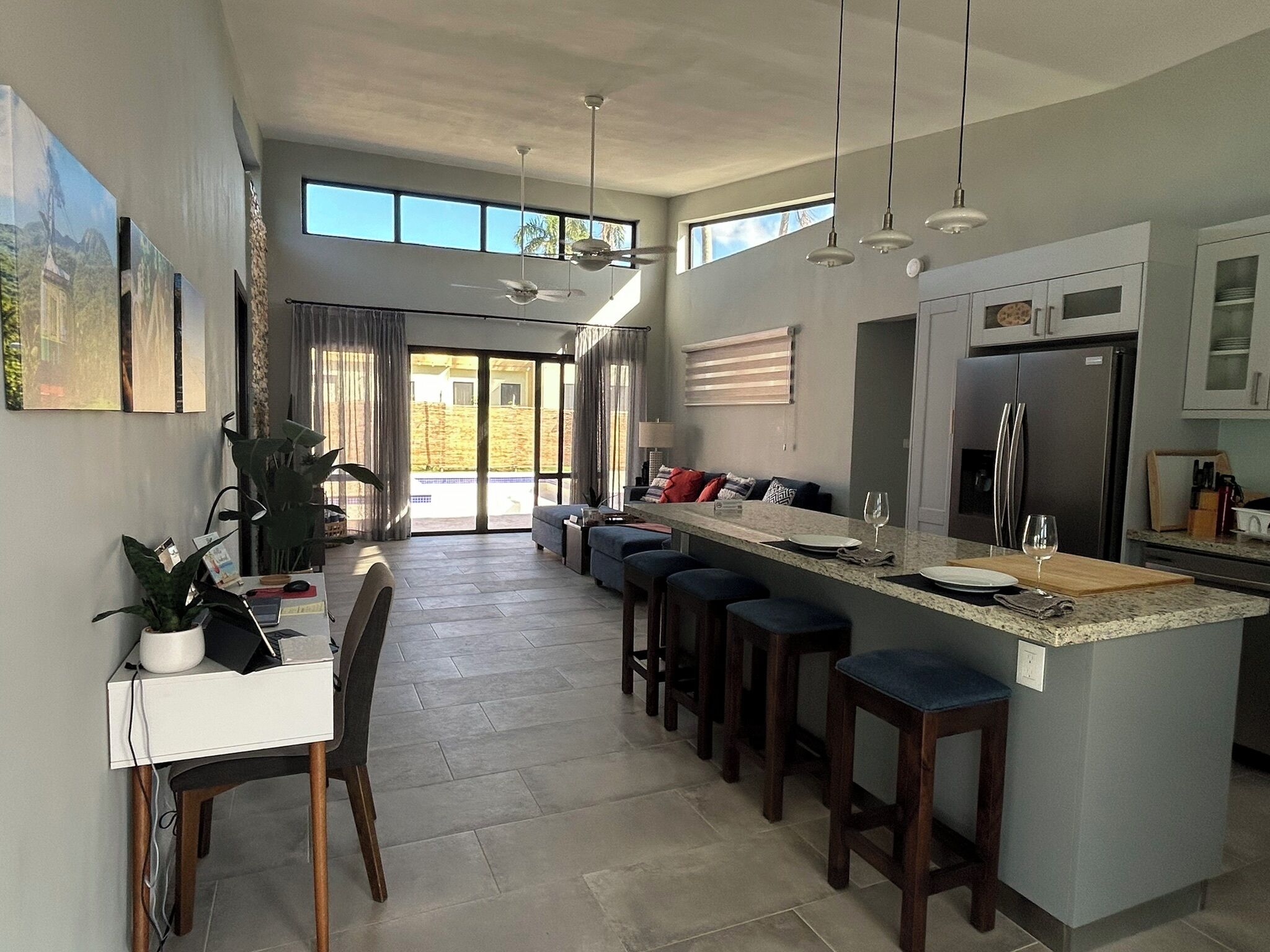 A modern kitchen with a large island, bar stools, and a dining area with a table and chairs.