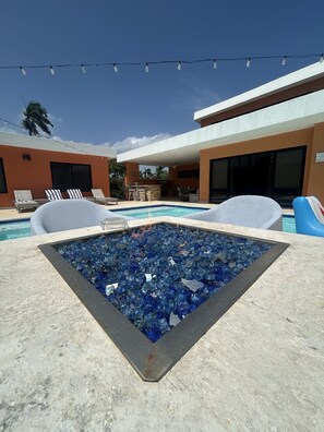 Ein Poolbereich mit Whirlpool, Liegestühlen, blauem Himmel und Lichterketten.