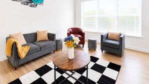 A living room with a grey sofa, a red chair, a round coffee table, and a black and white rug.