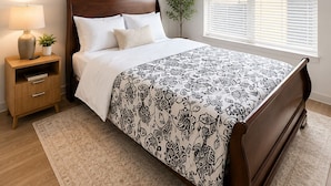 A bedroom with a bed, bedside table, lamp, window, and ceiling fan.