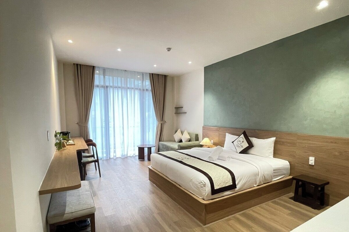 A modern hotel room with a large bed, a desk, and a chair.