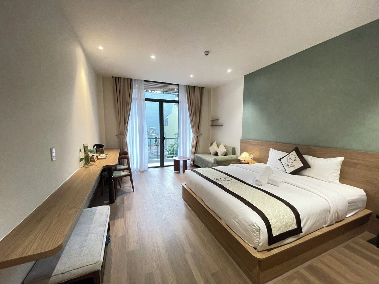 Une chambre d’hôtel avec un grand lit, un bureau, une chaise, une petite table et une vue sur l’extérieur.