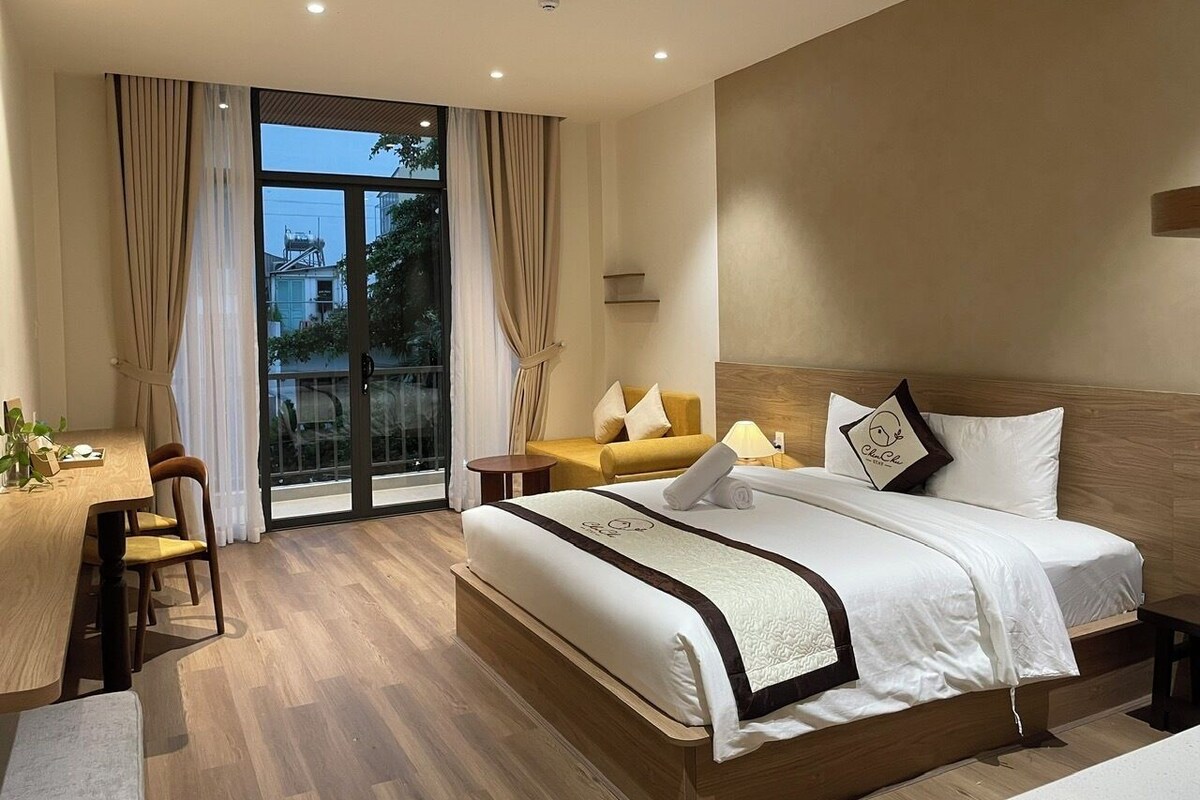 A hotel room with a large bed, a desk, and a sofa.