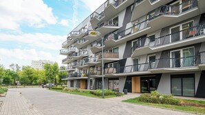 Ein mehrstöckiges Wohngebäude mit Balkonen, einem gepflasterten Weg und Grünflächen.