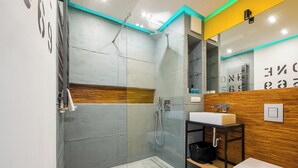 Ein modernes Badezimmer mit einer gläsernen Dusche, einem Holzkosmetikschrank und einem weißen Waschbecken.