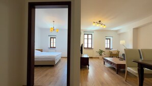 Une chambre d’hôtel avec un lit, un bureau, une chaise, une lampe et une fenêtre.