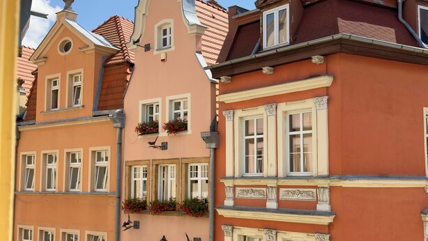 Une rangée d’immeubles à étages, chacun présentant un style architectural distinct, dont un bâtiment sur lequel on peut voir une enseigne indiquant « Debis ».