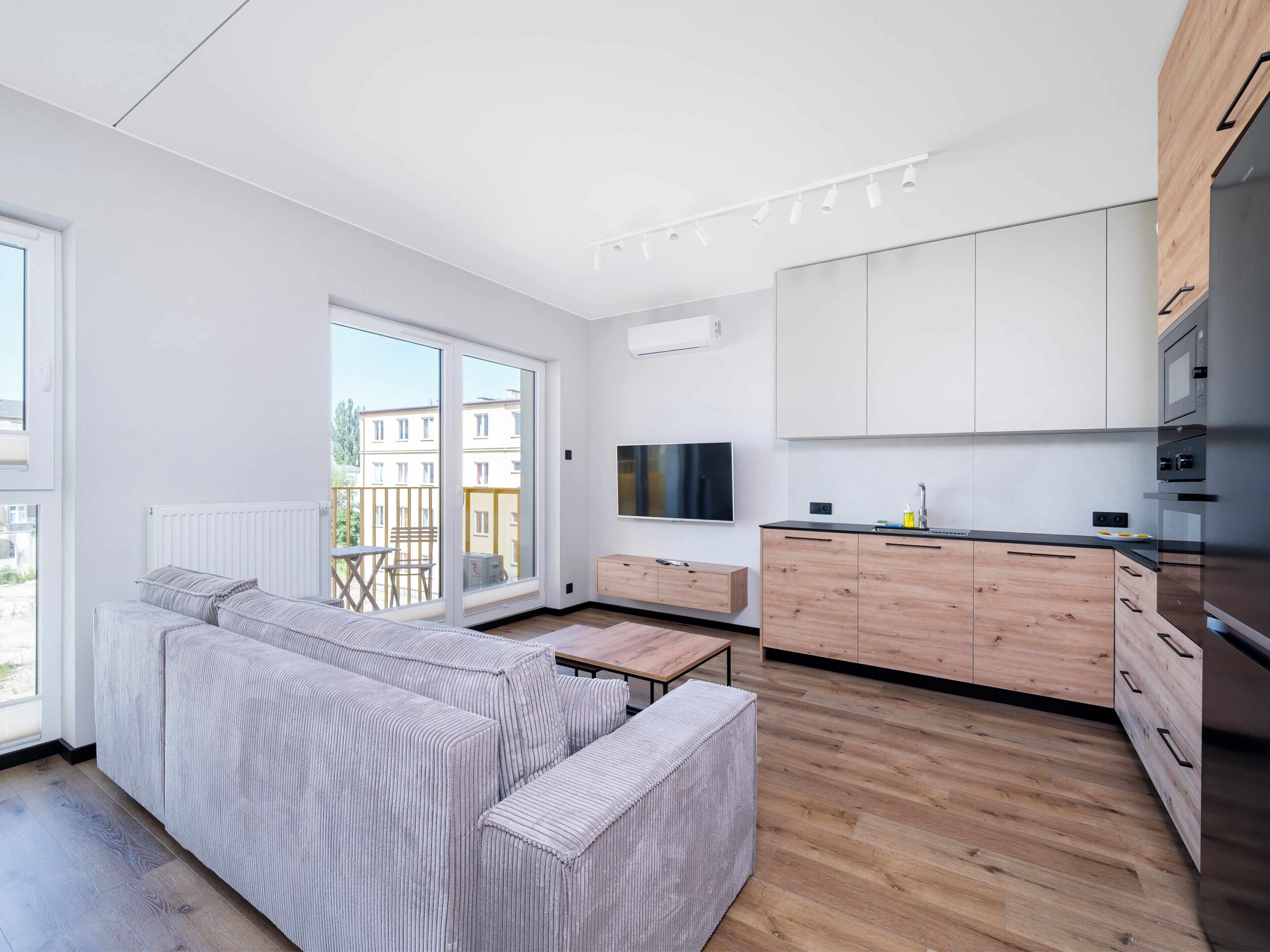 En modern lägenhet med soffa, matbord, kök och stora fönster.