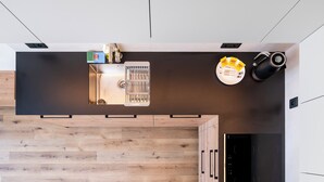 Eine moderne Küche mit Einbauofen, Kaffeemaschine und Spüle mit Fenster darüber.