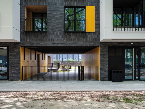 Un edificio moderno con entrada protegida por una reja, varias ventanas y un patio interior visible.
