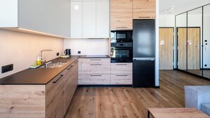Eine moderne Küche mit Holzausstattung, einem schwarzen Kühlschrank und einem eingebauten Backofen.