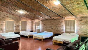 Une pièce avec quatre lits, des murs en briques et un plafond en pente.