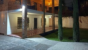 Une maison à deux étages avec un balcon, des murs en briques et un intérieur bien éclairé.
