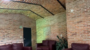 Une pièce aux murs de briques, avec une porte verte et trois canapés en cuir.
