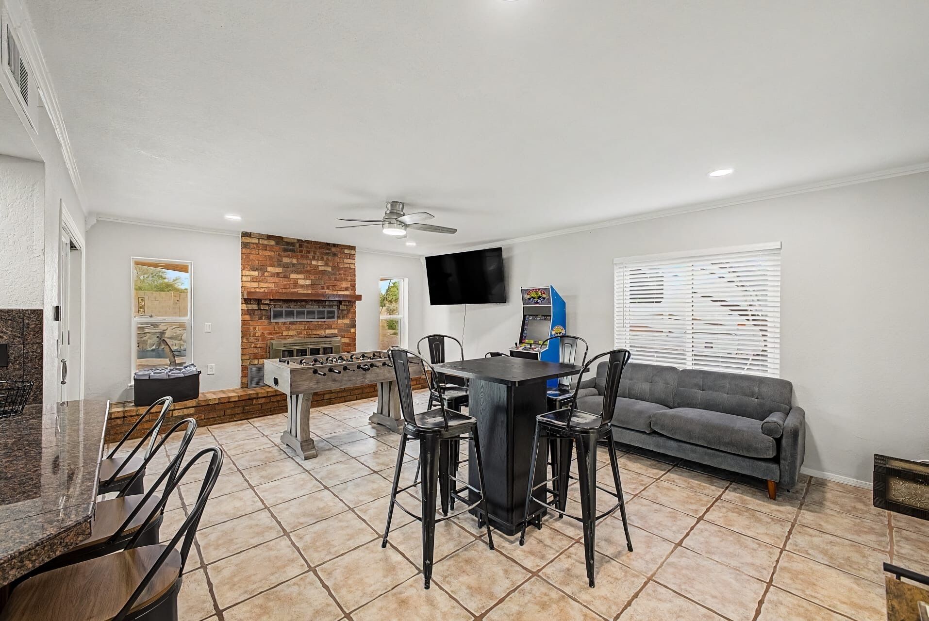 A living room with a fireplace, a television, a foosball table, and a sofa.