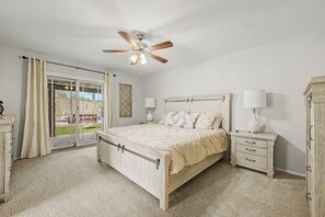 A bedroom with a bed, a nightstand, a dresser, a ceiling fan, and a view through a glass door. - Heated Private Pool at no extra charge, Arcade & BBQ, Prime N. Phoenix Location! (Phoenix)