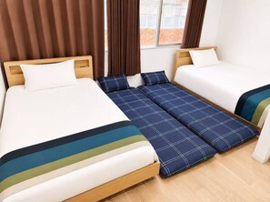 Een kamer met twee bedden, een uitslaapbank, bruine gordijnen en een raam met uitzicht.