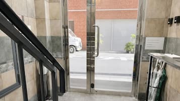 A hotel entrance with a glass door, a staircase, and a small table with umbrellas.