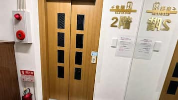 A hotel elevator with a fire alarm and emergency instructions.
