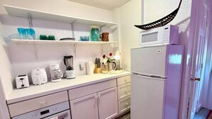 Uma cozinha equipada com micro-ondas, torradeira, máquina de café e frigorífico.