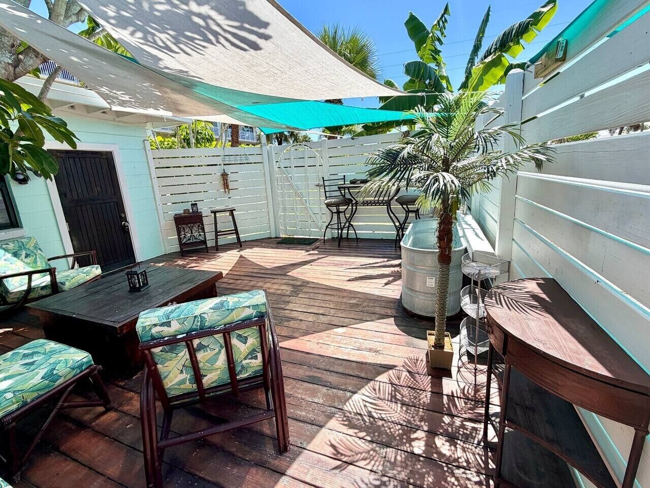 A patio with a wooden deck, outdoor furniture, a large umbrella, and a potted plant.