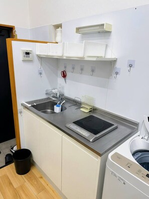 A compact kitchen with a sink, a built-in stove, a small countertop, and a washing machine. - 101 Melon Home/Near Nihonbashi & Dotonbori/5mins to Kuromon/5 guests (Osaka)
