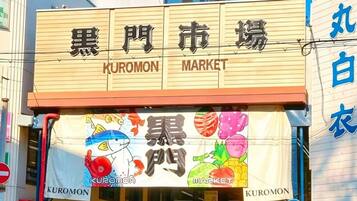A building with signage for 'KUROMON MARKET' and a colorful banner with illustrations of fish and fruits.