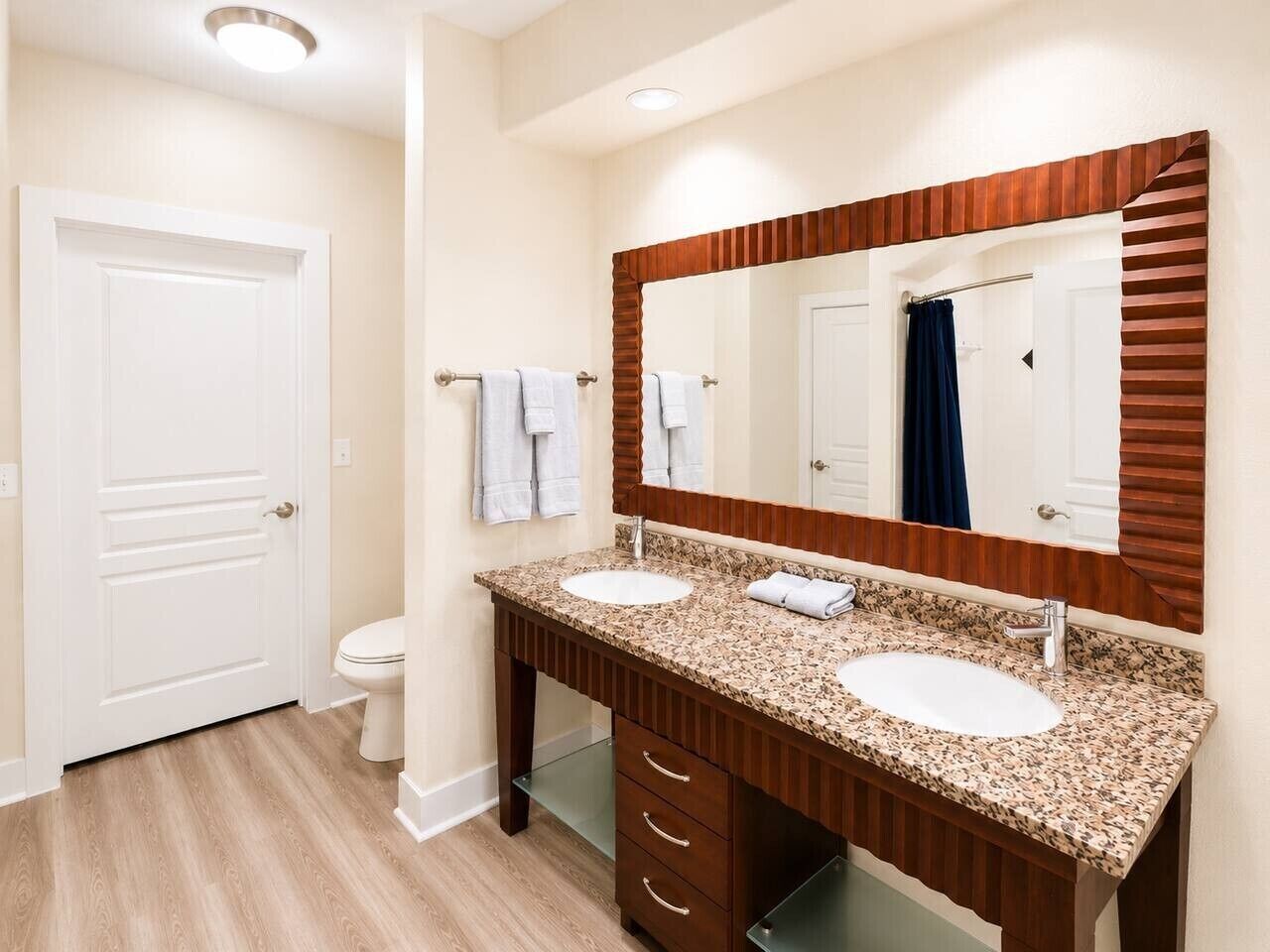 A bathroom with two sinks, a large mirror, and a toilet.