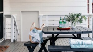 Katettu terassialue, jossa on pöytä ja penkkejä, kori sekä ruukussa oleva kasvi.
