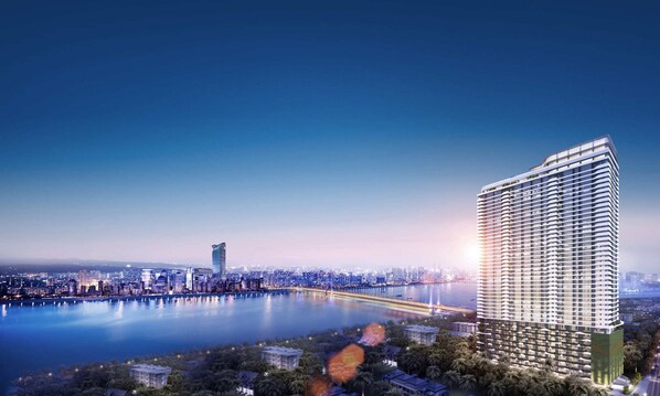 A high-rise hotel with a modern design, situated near a waterfront with a city skyline in the background. - Wealth Mansion (Phnom Penh)