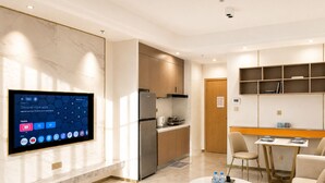 A modern kitchen with a built-in TV, a refrigerator, and a dining area with a table and chairs. - Wealth Mansion (Phnom Penh)
