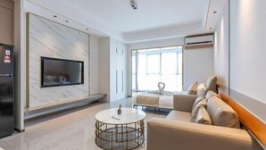 A modern living room with a flat-screen TV, a round coffee table, a sofa, and a fireplace. - Wealth Mansion (Phnom Penh)