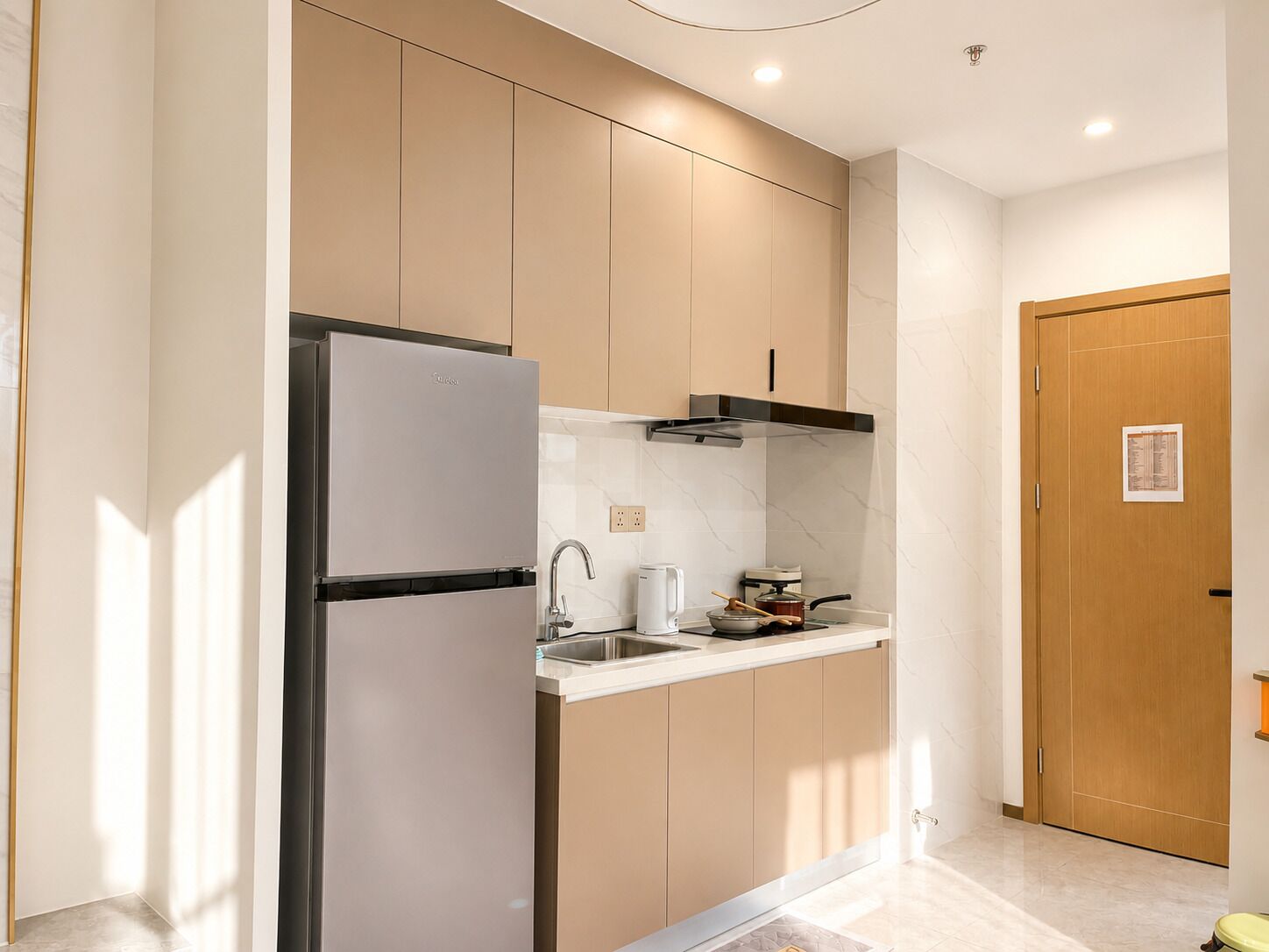 A compact kitchen with a refrigerator, sink, and stove.