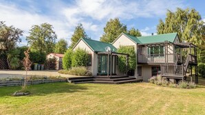 Ein zweistöckiges Haus mit einem grünen Dach, einer Veranda und einer Terrasse.