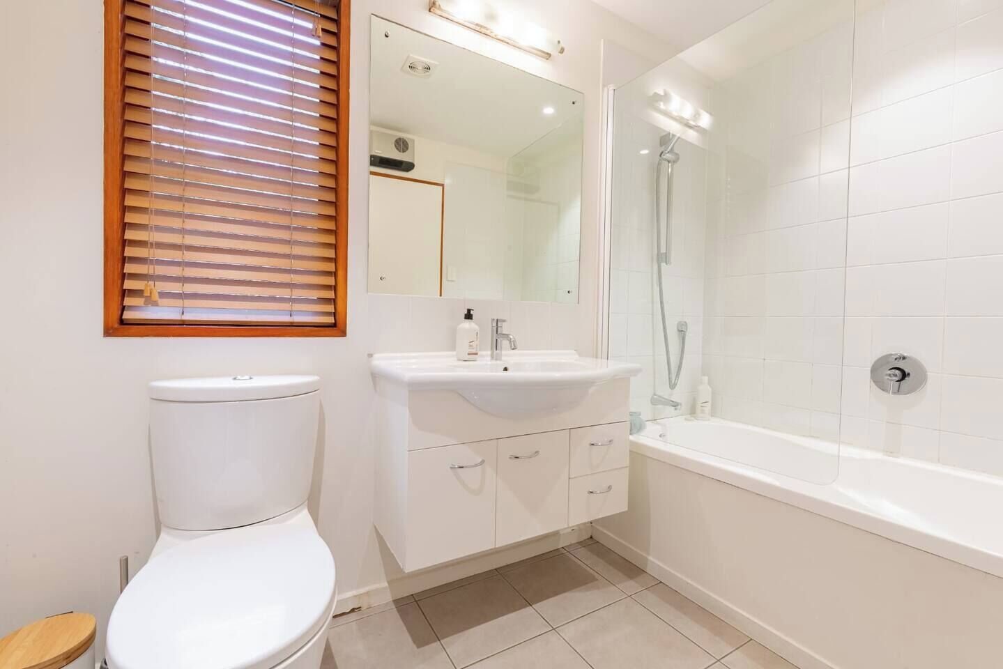 Een badkamer met toilet, wastafel, spiegel en douche.
