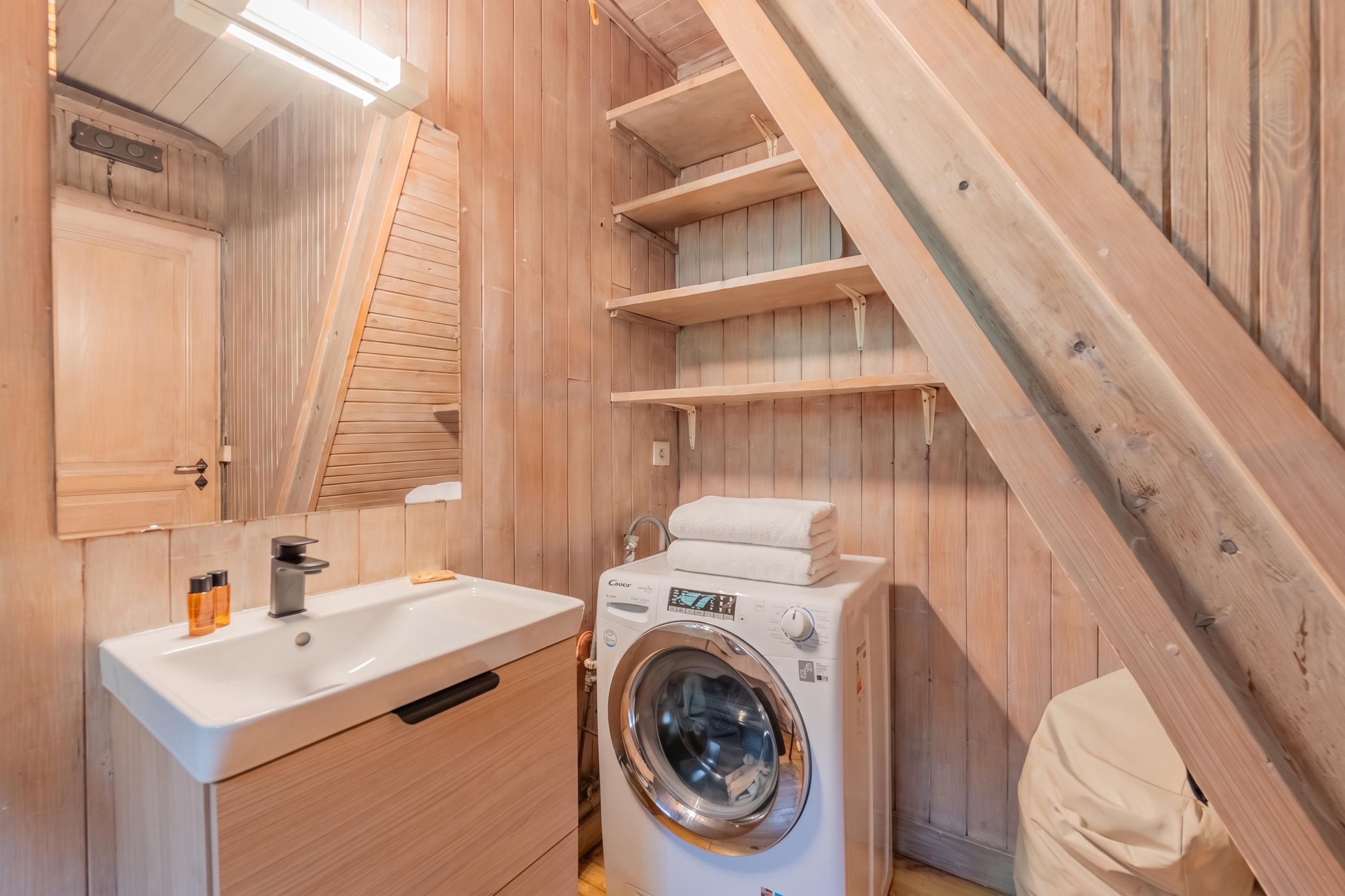 A wooden interior with a sink, mirror, and washing machine.