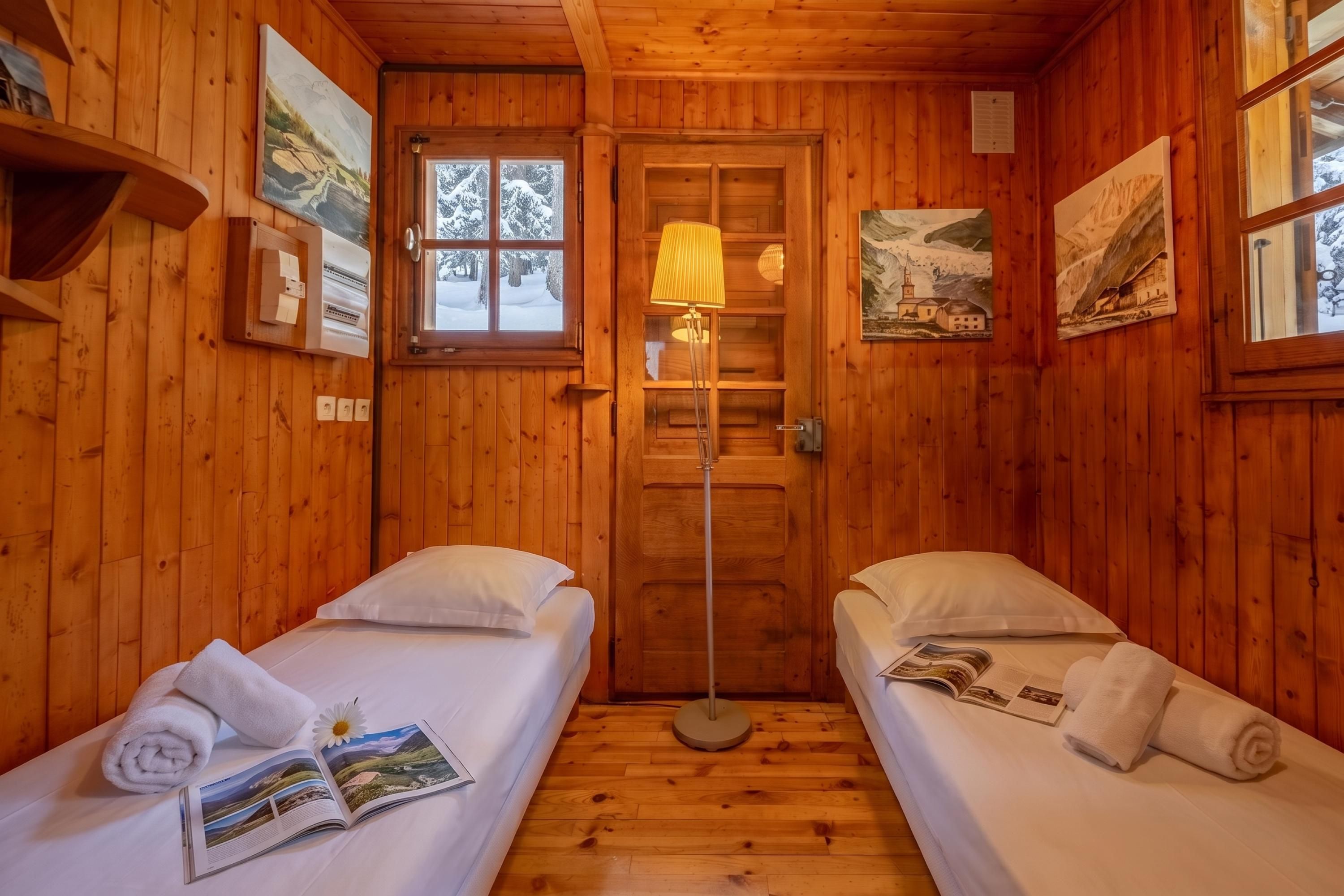 Une cabane avec deux lits, un plancher en bois, une porte et une fenêtre.