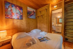 Ein Zimmer aus Holz mit einem Bett, zwei Bildern, einem Nachttisch und einer Nachttischlampe.