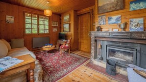 A wooden interior with a fireplace, a television, and a red patterned rug. - Chalet Petit Poucet 2BR Retreat in forest, Le Tour (Argentière), France (Le Tour (Argentière))