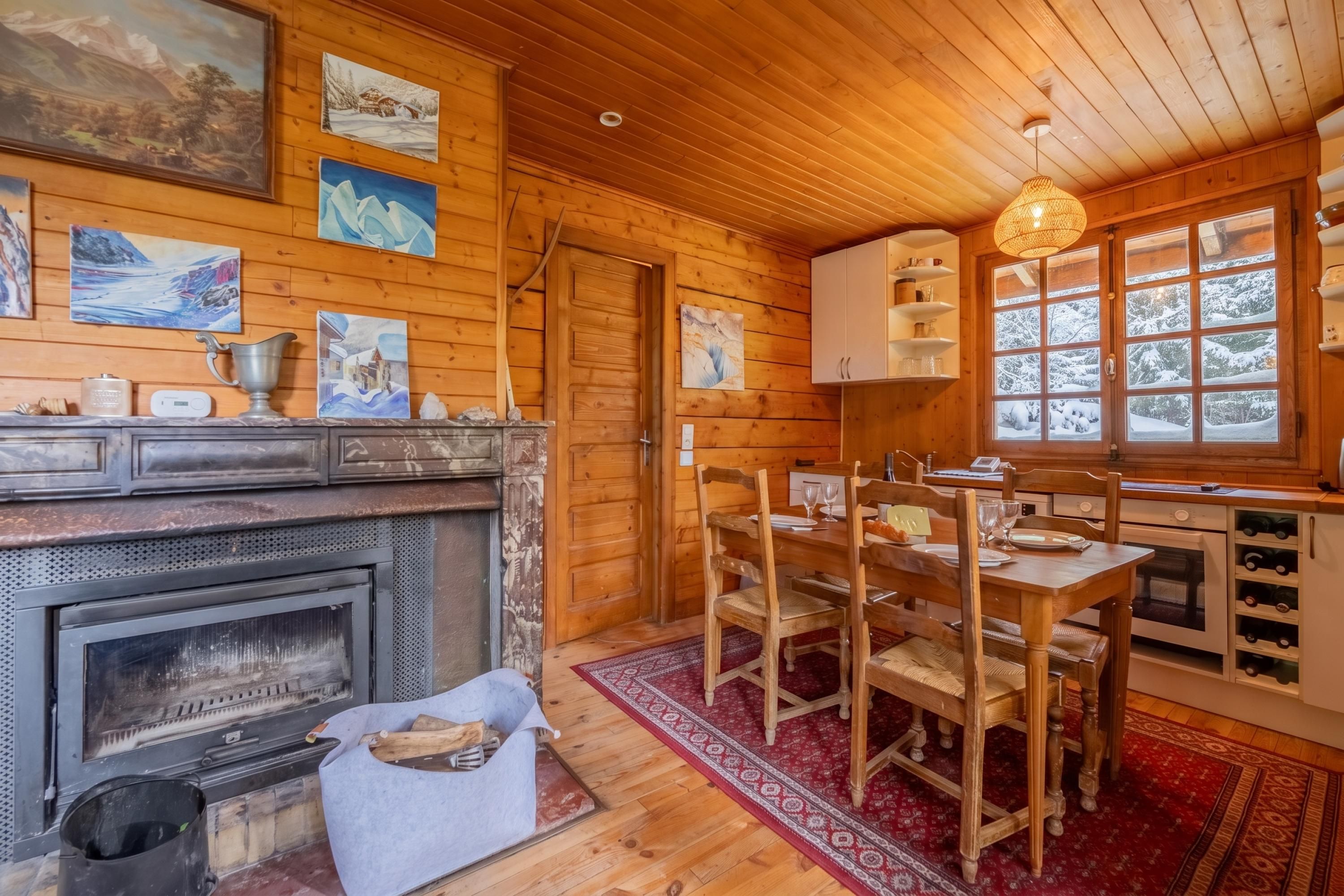 Interior acogedor de una cabaña con chimenea, paredes de madera y comedor.